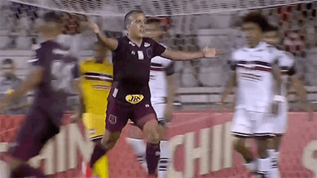 a soccer player in a maroon jersey with jb on his waist