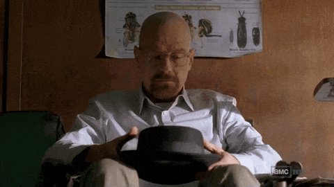 a bald man is sitting in a chair holding a hat in front of a poster that says a.m.c. on it