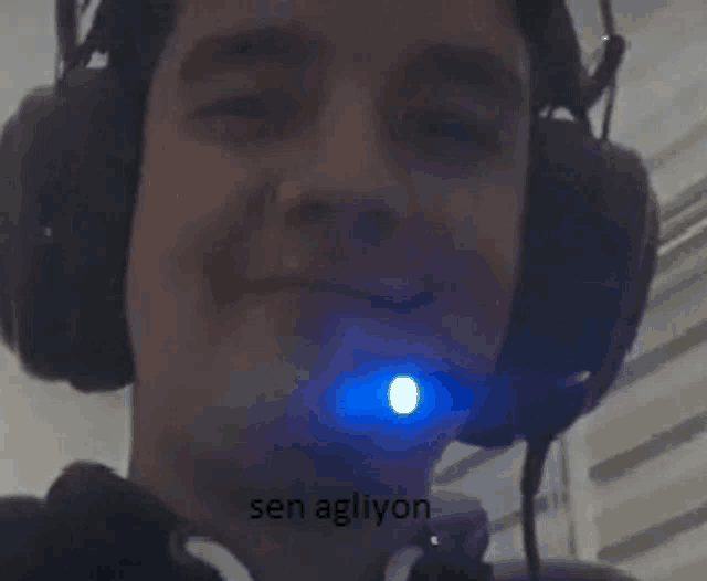 a man wearing headphones and a microphone with a blue light in his mouth .