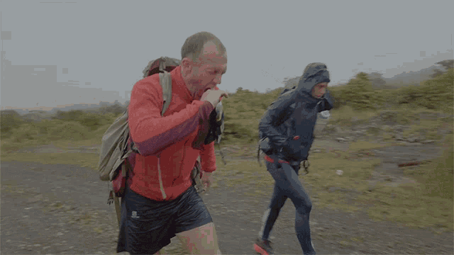 a man wearing a red jacket with the word salomon on the shorts