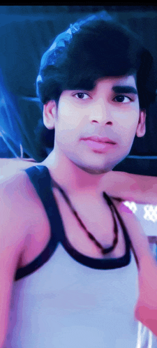 a young man wearing a white tank top and a necklace