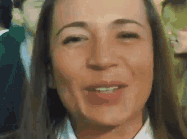 a woman with long hair is smiling and looking at the camera