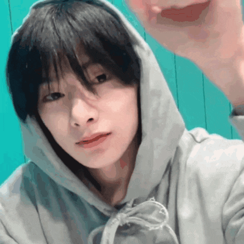 a close up of a person wearing a hoodie with their hand up