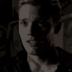 a close up of a man 's face in a dark room with a shadow on his face .