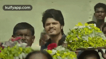 a man is standing in front of a crowd of people holding a bouquet of flowers .