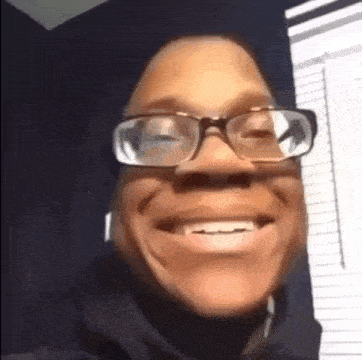 a man wearing glasses is smiling in a room .
