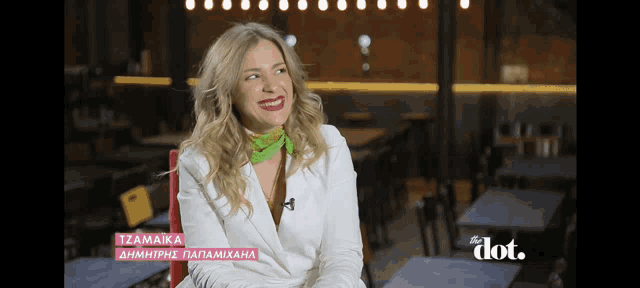 a woman in a white jacket is smiling in front of a sign that says tzamaika