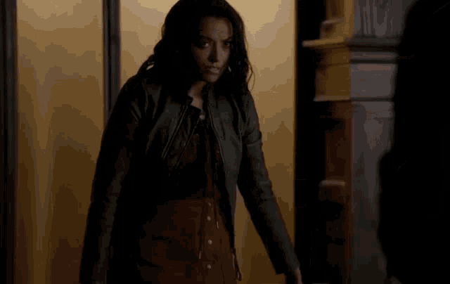 a woman in a leather jacket is standing in front of a door .