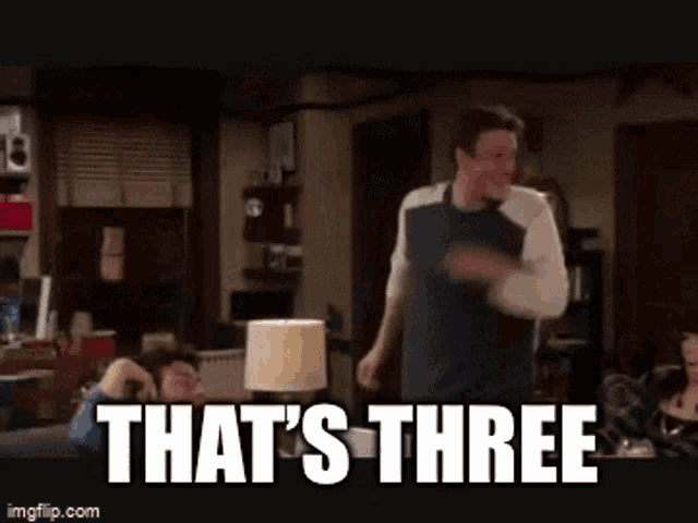 a man is dancing in a living room with the words that 's three on the screen .