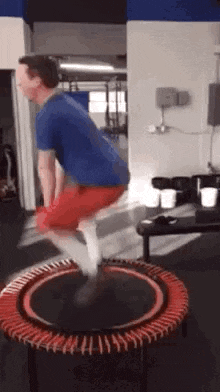 a man is jumping on a small trampoline in a gym .