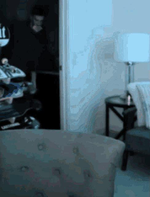 a blurred image of a living room with a couch and a lamp with the letter t on it