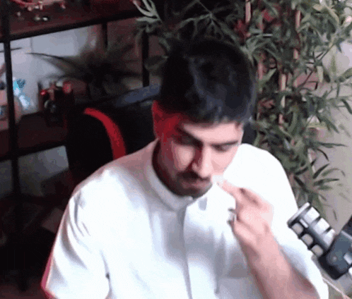 a man in a white shirt is blowing his nose