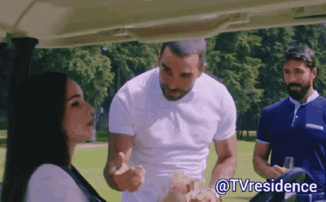 a man talking to a woman in a golf cart with @tvresidence written below it