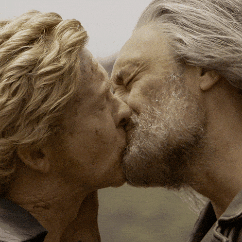 a man with a beard and blonde hair kisses another man
