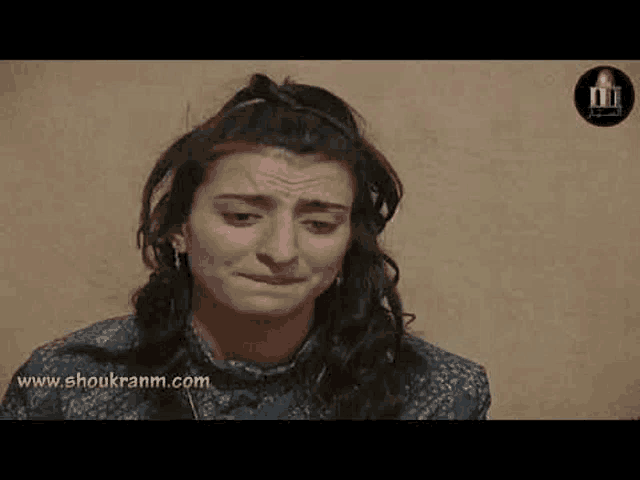 a woman is making a funny face while sitting in front of a wall .