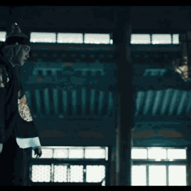 a man in a traditional korean costume is walking through a dark room .