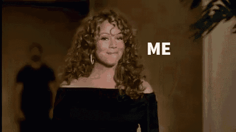 a woman with curly hair is covering her mouth with her hand and the word me is on the screen .