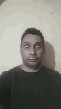 a man with a beard and a black shirt looks at the camera