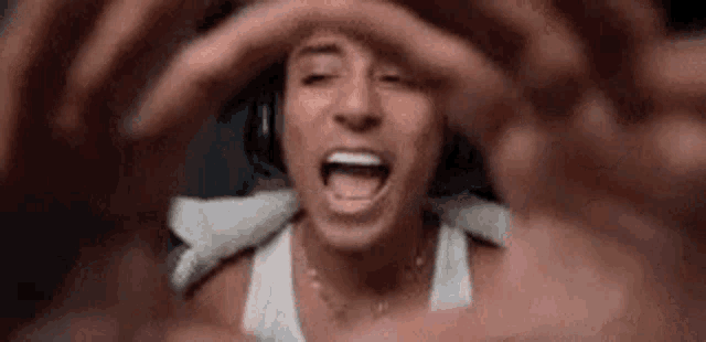 a man wearing headphones is making a heart shape with his hands while screaming .