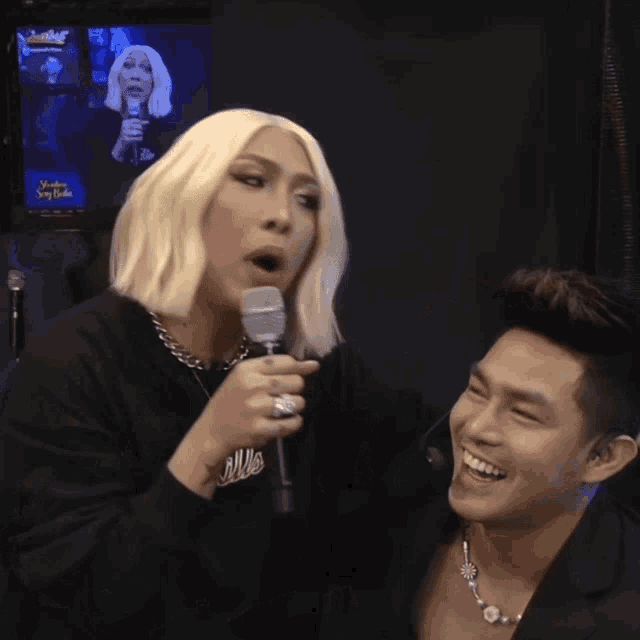 a man in a blonde wig is kissing another man on the neck