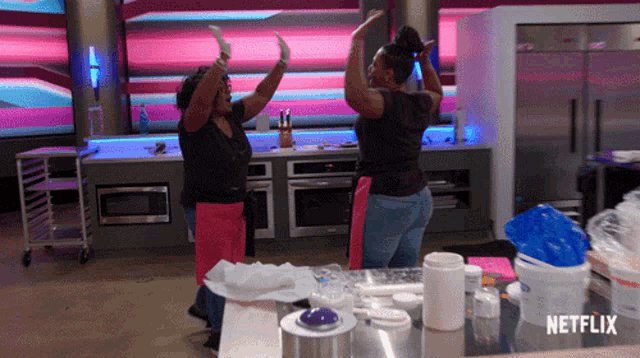 two women are dancing in a kitchen with a netflix logo in the background