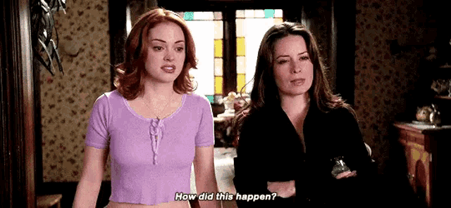 two women are standing next to each other in a hallway .