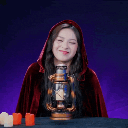 a woman in a red cape holds a lantern