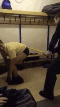 a man in a yellow shirt is squatting down in a locker room