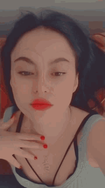 a woman with red nails is taking a selfie with her hand on her face