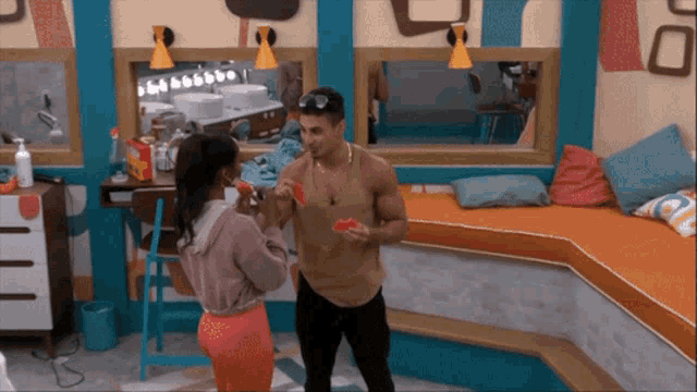 a man and a woman eating watermelon in a room