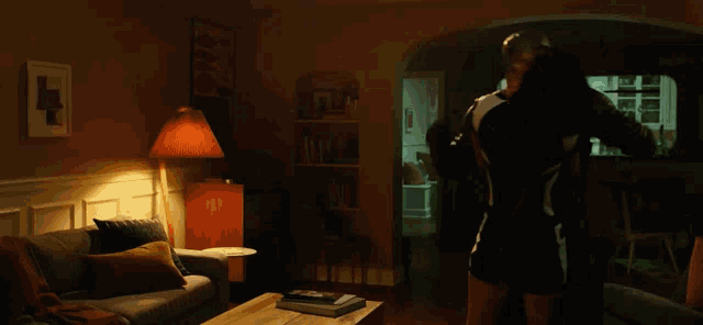 a man sits on a couch in a dark living room with a lamp