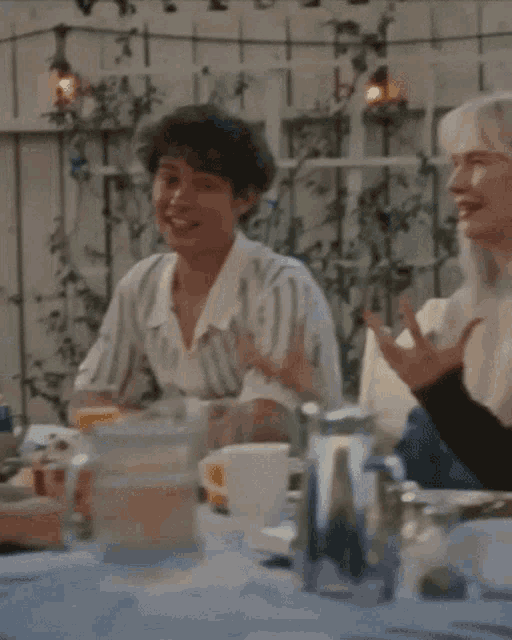a man in a striped shirt sits at a table with a woman