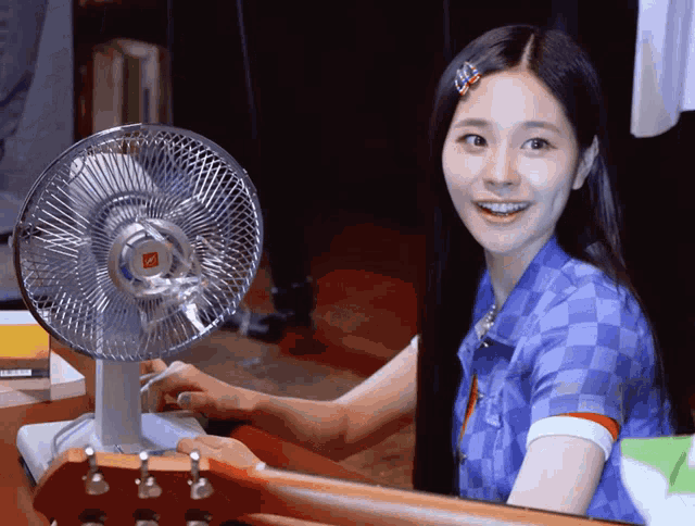 a woman in a blue shirt is smiling in front of a fan that says nc