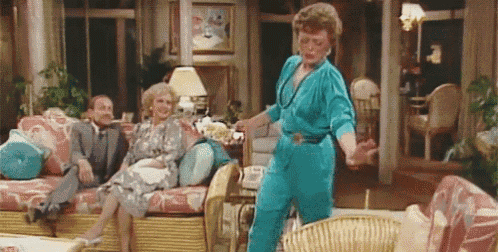 a woman in a blue jumpsuit is dancing in a living room .