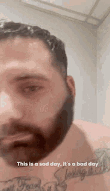 a man with a beard and a tattoo on his chest says this is a sad day