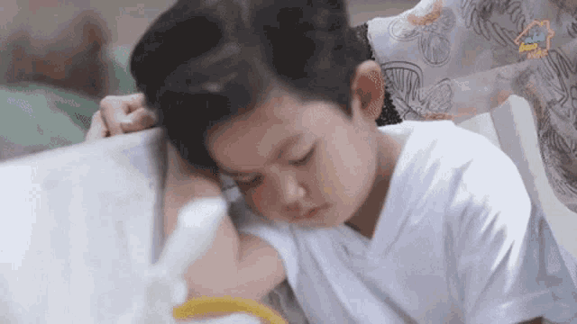 a little boy laying on a bed with a woman holding his head and the word home on the bottom right