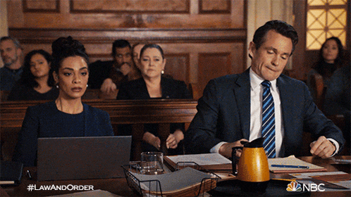 a man and a woman are sitting at a table in a courtroom with nbc written on the bottom right