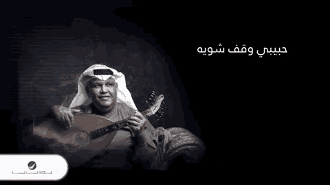 a man in a turban is holding a guitar in front of a black background