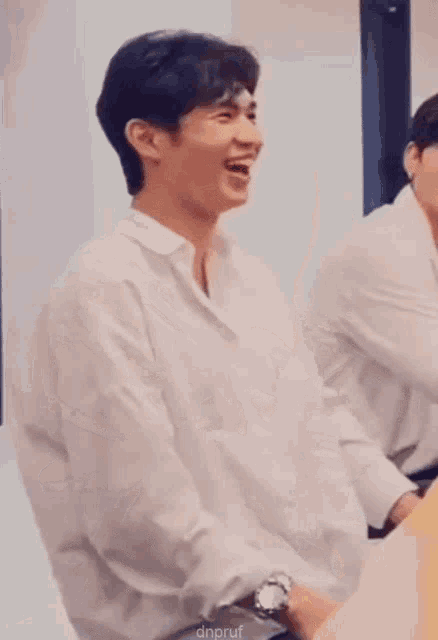 a man in a white shirt is clapping his hands while sitting down .
