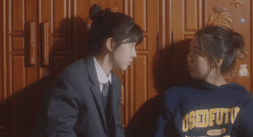 two girls are standing next to each other and one has a sweatshirt that says used futo