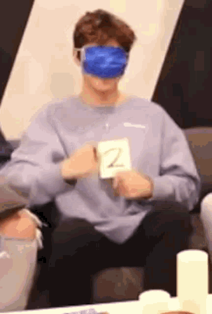 a man wearing a blue face mask is sitting on a couch holding a card with the letter z on it .