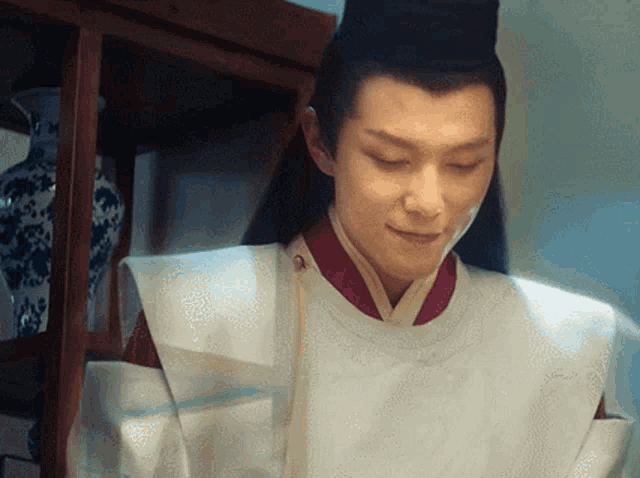 a man wearing a white robe and a black hat looks down