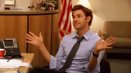 a man in a shirt and tie is sitting at a desk with his arms outstretched .