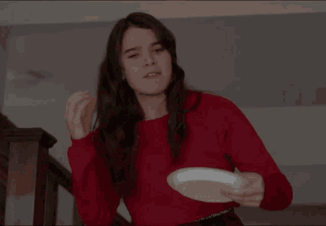 a woman in a red sweater holds a white plate