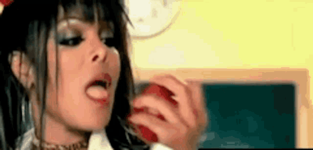 a woman is eating an apple in front of a blackboard in a classroom .