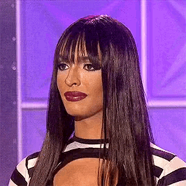 a woman with long hair and a fringe is wearing a striped shirt and lipstick .