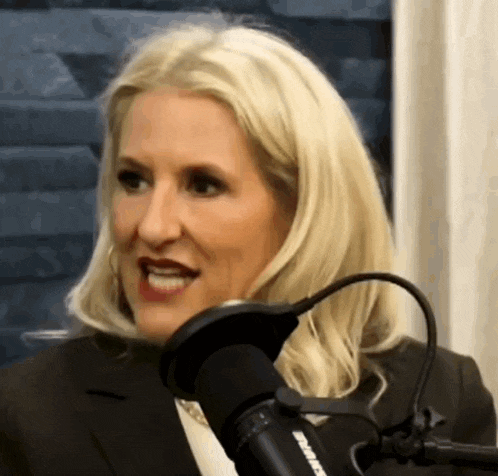 a woman in a suit is talking into a microphone that says siriusxm on it