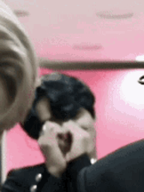 a woman is making a heart shape with her hands while a man looks on .