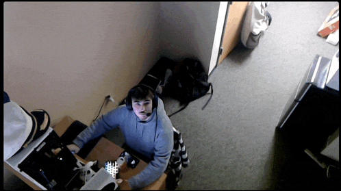 a man wearing headphones sits at a desk in a dark room