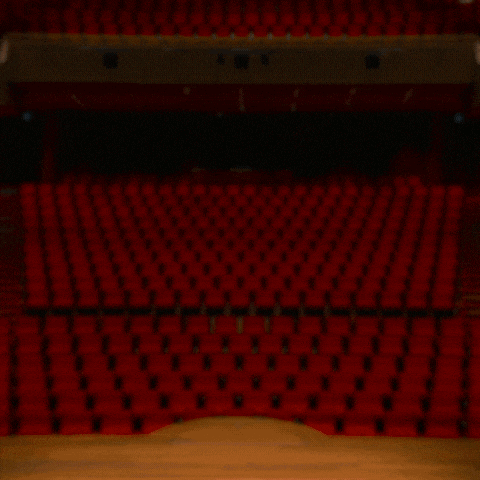a man and a woman are standing in front of empty red seats